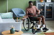© Seventyfour - Full length portrait of young black man with disability exercising at home using dumbbell, copy space