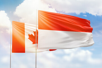 Sunny blue sky and flags of indonesia and canada