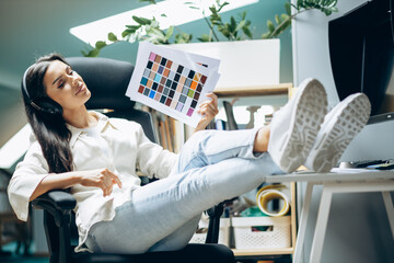 Wall Mural - Woman designer listening to music and working at an office