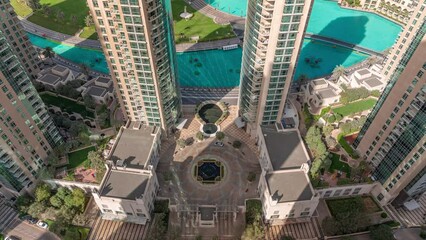 Wall Mural - Dubai Downtown cityscape looking down view with shadows from tallest skyscrapers near lake aerial timelapse. Fountains and busy roads with traffic from above