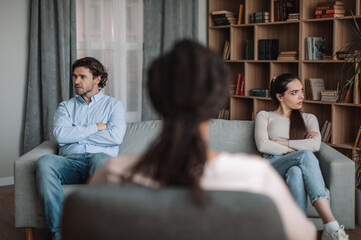 Wall Mural - Angry sad millennial european husband and wife ignore each other, don't want to speak with black doctor