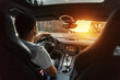 © alones - Man in a premium car with an interior is driving at sunset. Concept travel by car