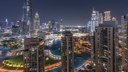 Wall Mural - Dubai Downtown cityscape with tallest skyscrapers around walking area aerial night timelapse. Construction site of new towers and busy roads with traffic from above