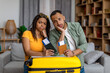 Sad african american spouses with passports and plane tickets leaning on suitcase, missed their vacation