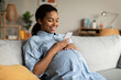© Prostock-studio - Pregnant African Woman Using Mobile Phone Texting Sitting At Home