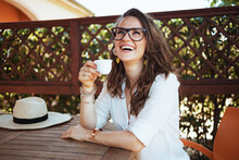 Happy Stylish Woman In Shirt Sitting At Table Drinking Coffee