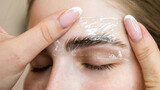 Fototapeta  - The master uses a plastic film during lamination of the eyebrows.