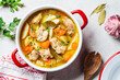 © vaaseenaa - Chicken stew with potatoes and carrots in red saucepan. Chicken soup with vegetables and herbs. Comfort food recipe.