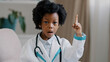 © Yuliia - Close-up little cute pretty kid girl in medical clothes pretending to be doctor plays looking at camera posing raises index finger comes up with idea remembers creates plan future profession concept