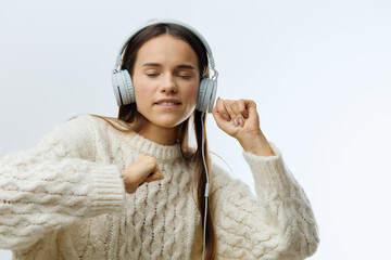 Wall Mural -  emotional, playful woman listens to music in fashionable headphones, closing her eyes with pleasure and raising her hands into a fist. Horizontal photo with space for inserting an advertising layout