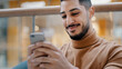 Close-up young arab guy holding phone looking at screen smartphone smiling receive nice email message browsing web on dating site checks social network enjoys free wifi confirms order in online store