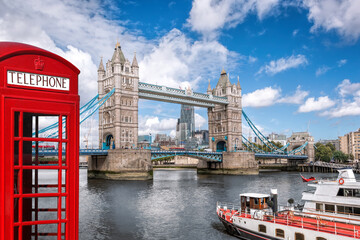 Fototapete - Tower bridge with boat against red phone booth in London, England, UK