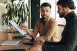 © Prostock-studio - Partnership concept. Two serious businessmen studying documents, discussing business deal in office interior