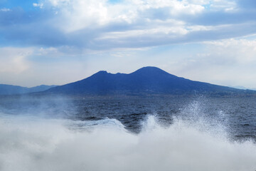 Wall Mural - Blue landscape background. Vesuvius mount and waves of the Tyrrhenian Sea seen from a ferryboat, Naples, Italy