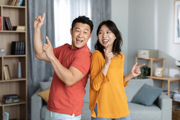 Funny asian man and woman having good time at home