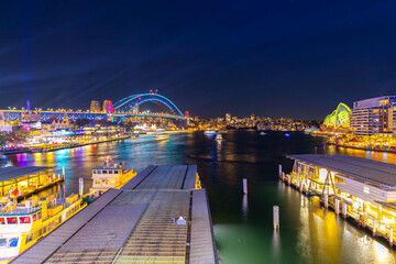 Wall Mural - Colourful Light show at night on Sydney Harbour NSW Australia. The bridge illuminated with lasers and neon coloured lights 