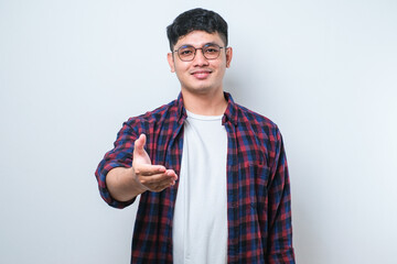 Wall Mural - Asian young man wearing casual clothes smiling friendly offering handshake as greeting and welcoming