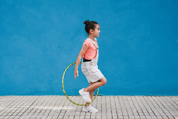 Wall Mural - Cute little girl with hula hoop ring - Child having playful time in the city