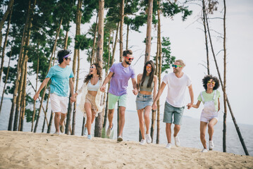 Sticker - Full length portrait of friendly overjoyed people hold arms running sand beach hanging out outdoors