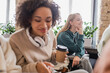 © LIGHTFIELD STUDIOS - smiling student listening lecture near blurred african american classmate with headphones and coffee to go.