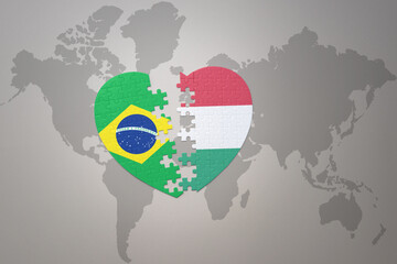 Wall Mural - puzzle heart with the national flag of brazil and hungary on a world map background.Concept.