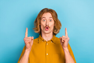 Wall Mural - Portrait of attractive stunned long-haired guy demonstrating up copy space isolated over bright blue color background