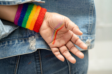 Asian lady wearing rainbow flag wristbands, symbol of LGBT pride month celebrate annual in June social of gay, lesbian, bisexual, transgender, human rights.