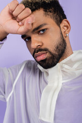 Wall Mural - portrait of bearded and young african american man with blue eyes isolated on purple.