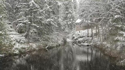 Wall Mural - Floating over a lake in winter with the snow falling and calm water.