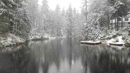 Wall Mural - Floating over a lake in winter with the snow falling and calm water.