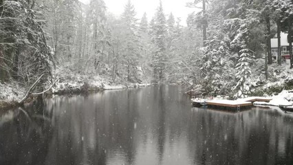 Wall Mural - Floating over a lake in winter with the snow falling and calm water.