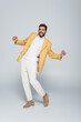 © LIGHTFIELD STUDIOS - full length of excited african american man in stylish outfit posing on grey.