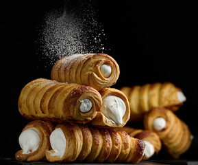 Canvas Print - Baked tubules filled with whipped egg whites cream on a black wooden kitchen board