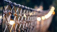 Rope Bridge Decorated With Warming Bulb Light At Twilight Evening
