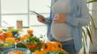 © alex_marina - A Pregnant Woman Using a Tablet Prepares Healthy Food in a Bright Kitchen With a Modern Interior. Taking Care of Children. Woman Chooses the Right Food. Organic. Close-up.