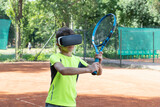 Fototapeta Tulipany - Close up image of boy in vr glasse on tennis court with raquet in his hands. Training process in cyberspace with virtual coach.