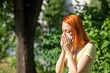 © Adam Radosavljevic - Young redhair woman sneezing in park. Pollen Allergy symptoms