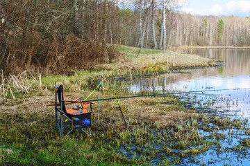 Wall Mural - landscape with a fishing chair on the lake shore, fishing equipment - fishing rods, fishing feed and landing net, fishing hobby