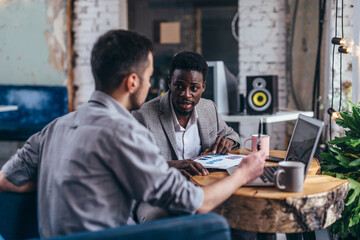 Wall Mural - Business partners in a meeting together with a young man using a laptop and African American man.