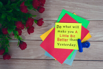 Wall Mural - Motivational quote on colorful note with artificial flower on wooden background.