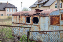 A Dilapidated Rotten And Rusty Metal Hut On A Work Site. An Old Tin Construction Trailer With A Round Roof And A Broken Window From A Meadow Or Pasture With A Trailer Drawbar.
