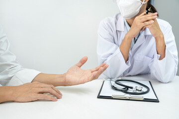 Wall Mural - A female doctor in medical mask is listening symptom from patient during discussing about diagnosis of disease