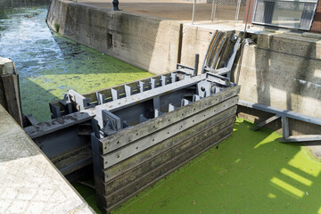 Manual canal boat lock in a river full of algae 