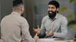 © Yuliia - Two multiracial arabic hispanic colleagues businesspeople men discuss startup accept common project satisfied with result of negotiation give high five agreement partnership teamwork at office meeting