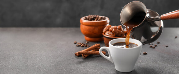 Pouring of hot coffee from cezve into cup on table