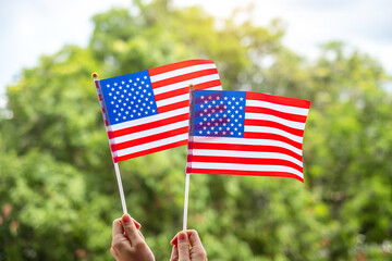 Wall Mural - hand holding United States of America flag on green background. USA holiday of Veterans, Memorial, Independence ( Fourth of July) and Labor Day concept