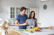 © BestForYou - Romantic young couple cooking together in the kitchen having a great time together.