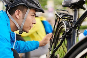 Poster - Frowning cyclist in protective tuve helmet checking bicycle wheels before ride