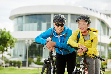 Poster - Portrait of happy active young Asian couple with bicycles smiling at camera