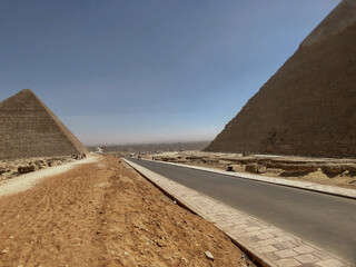 Wall Mural - Popular tourist destination ancient Egyptian Giza city ruins of the pyramids of Gizeh close to Cairo with the Pyramid of the Cheops and the Pyramid of Chephren and prehistoric stone walls tombs